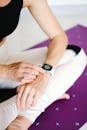 Close-up of woman adjusting smartwatch while sitting on a yoga mat, focusing on fitness and technology.